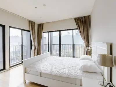 Spacious bedroom with large windows and elegant curtains, offering abundant natural light and a serene atmosphere.