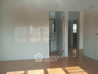 Spacious room with open doors and natural light, showcasing glossy tiled flooring.