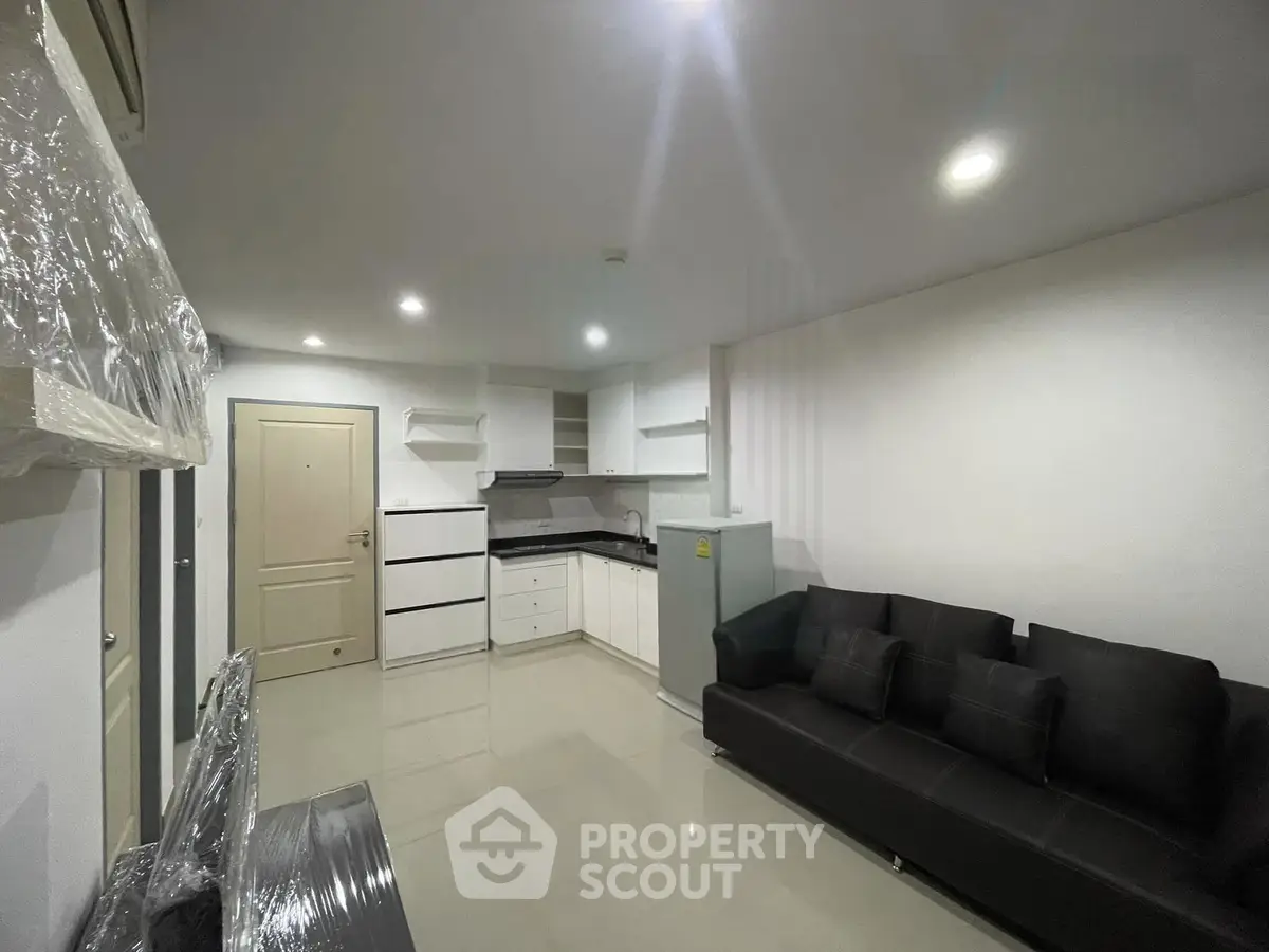 Modern living room with sleek black sofa and compact kitchen in open layout
