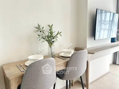 Modern dining area with sleek wooden table and chairs, featuring a mounted TV and elegant decor.