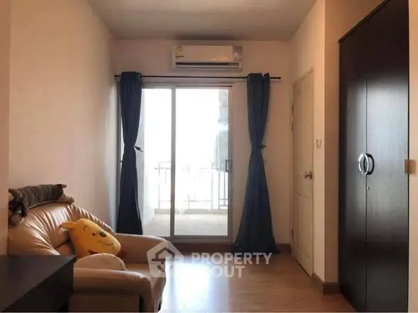 Cozy living room with balcony access and air conditioning, perfect for relaxation.