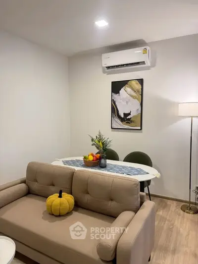 Cozy living room with modern decor, featuring a stylish sofa, dining table, and wall art under soft lighting.
