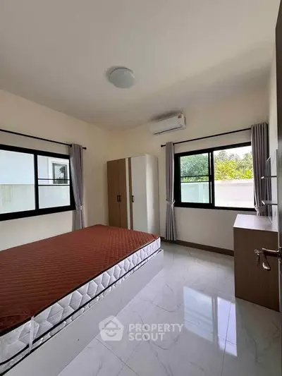 Spacious bedroom with large windows and modern furnishings in a serene setting.