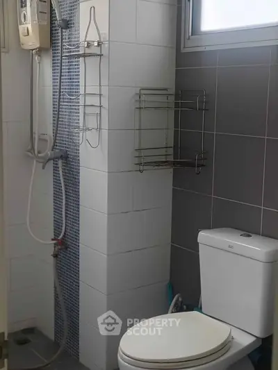 Modern bathroom with shower and toilet in sleek tiled design.