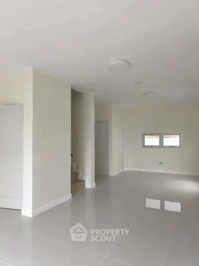 Spacious empty room with glossy tiled floor and staircase