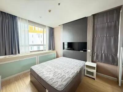 Modern bedroom with large window and stylish decor in urban apartment.