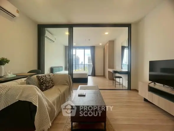 Modern living room with open layout and city view, featuring stylish furniture and natural light.