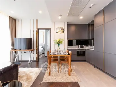 Modern open-layout living room with sleek kitchen and dining area, featuring stylish furniture and elegant decor.