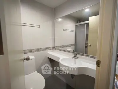 Modern bathroom with sleek fixtures and large mirror in a contemporary apartment.