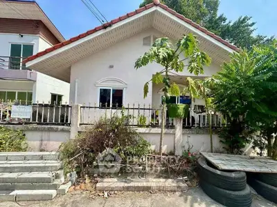 Charming single-story house with a fenced yard and lush greenery, perfect for family living.