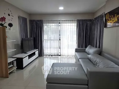 Modern living room with sleek gray sofa and large TV, featuring elegant curtains and glossy tiled floor.