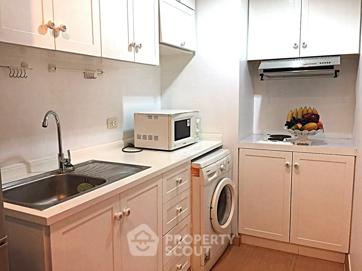 Charming kitchen with white cabinetry, washing machine, and microwave, perfect for modern living.