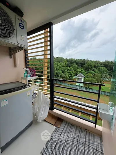 Charming balcony with lush green view and modern appliances, perfect for relaxation and utility.
