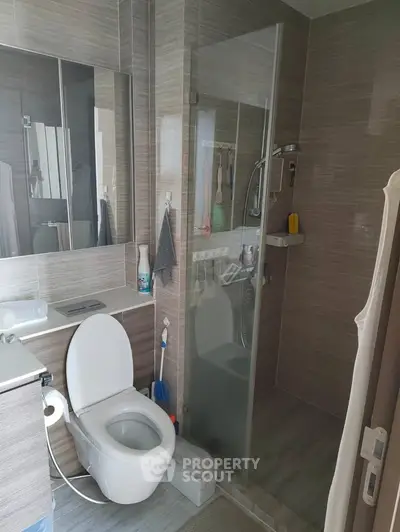 Modern bathroom with glass shower and sleek fixtures in contemporary apartment.