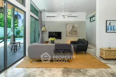 Modern living room with pool view, stylish furniture, and large windows for natural light.