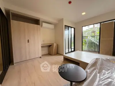 Modern minimalist room with large windows and garden view, featuring sleek wooden flooring and built-in wardrobe.