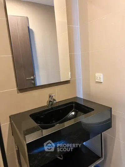 Modern bathroom with sleek black countertop and mirror in contemporary home.