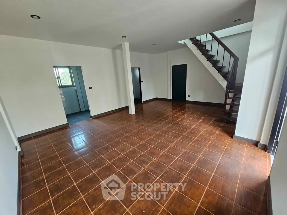 Spacious open-plan living area with elegant wooden flooring and modern staircase.