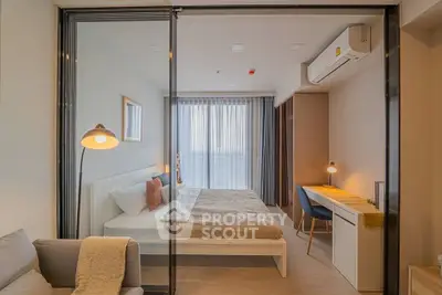 Modern bedroom with cozy decor and workspace, featuring large windows and stylish furnishings.