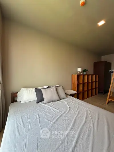Spacious bedroom with modern decor and ample natural light, featuring a cozy bed and stylish shelving unit.
