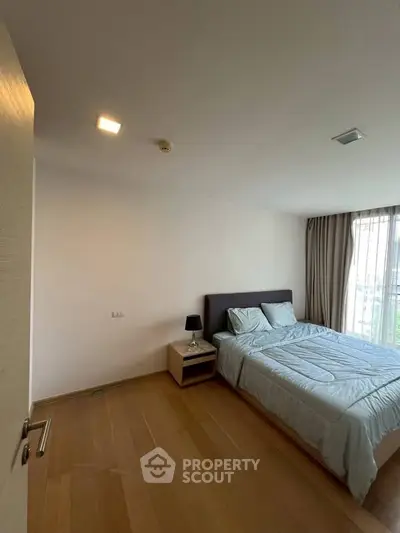 Spacious bedroom with natural light and modern furnishings in a stylish apartment.