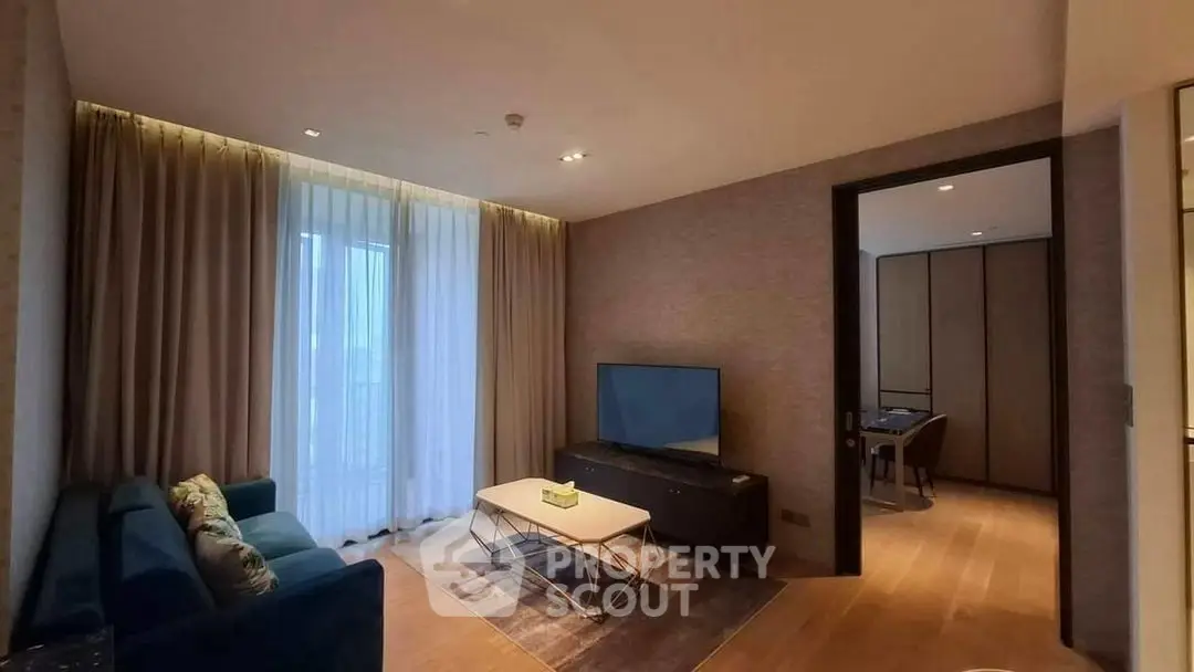 Modern living room with elegant decor and natural light, featuring a cozy seating area and a flat-screen TV.