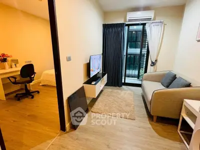 Modern living room with cozy sofa, TV, and balcony access in stylish apartment.