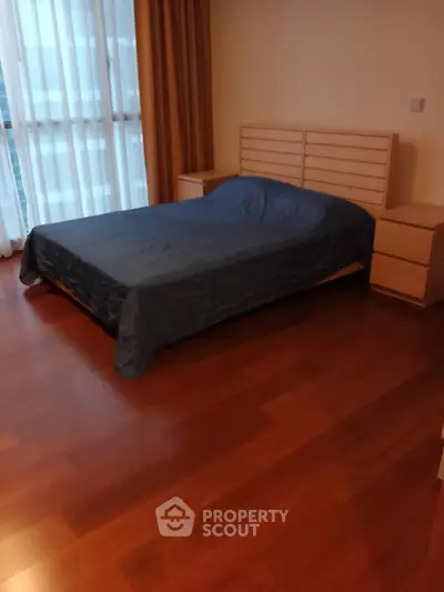 Spacious bedroom with wooden flooring and modern furniture