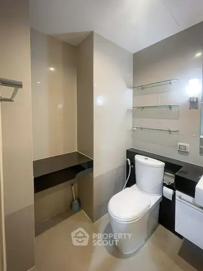 Modern bathroom with sleek fixtures and glass shelving in a contemporary apartment.