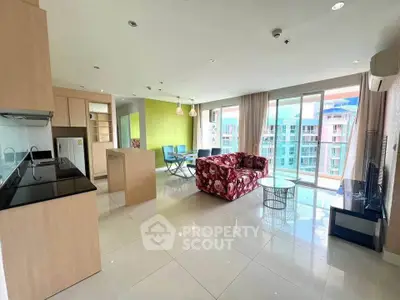 Spacious modern living room with open kitchen and balcony view in high-rise apartment.