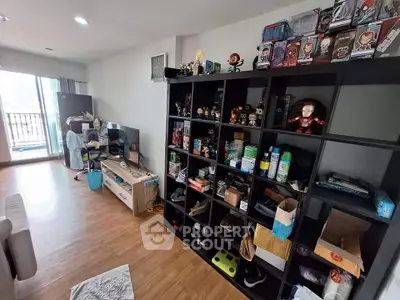 Spacious living room with wooden flooring and large shelving unit, perfect for collectors.