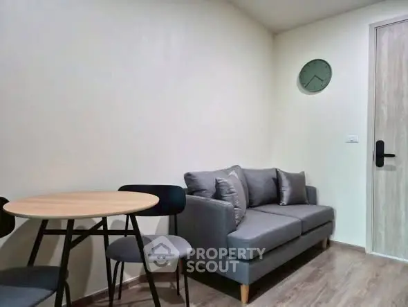 Cozy living room with modern gray sofa and round dining table, perfect for small apartments.