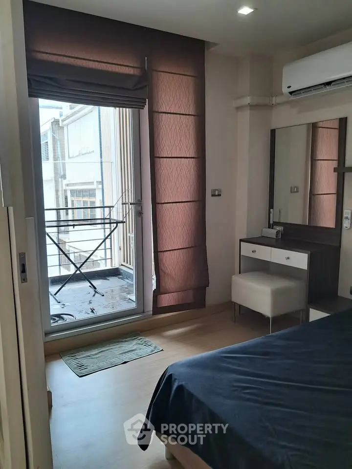 Cozy bedroom with balcony access and modern furnishings in urban apartment