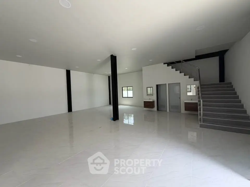 Spacious modern interior with sleek staircase and open layout, ideal for versatile living or commercial use.