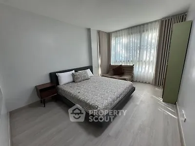 Spacious bedroom with modern decor and large windows for natural light
