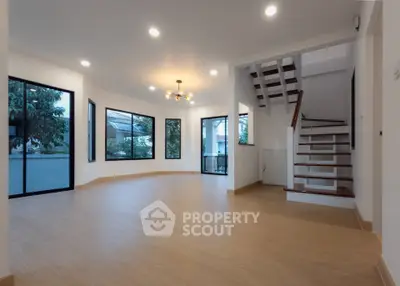 Spacious modern living room with large windows and elegant staircase