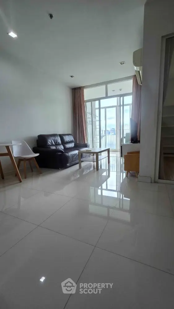 Spacious modern living room with sleek furniture and large windows offering abundant natural light.