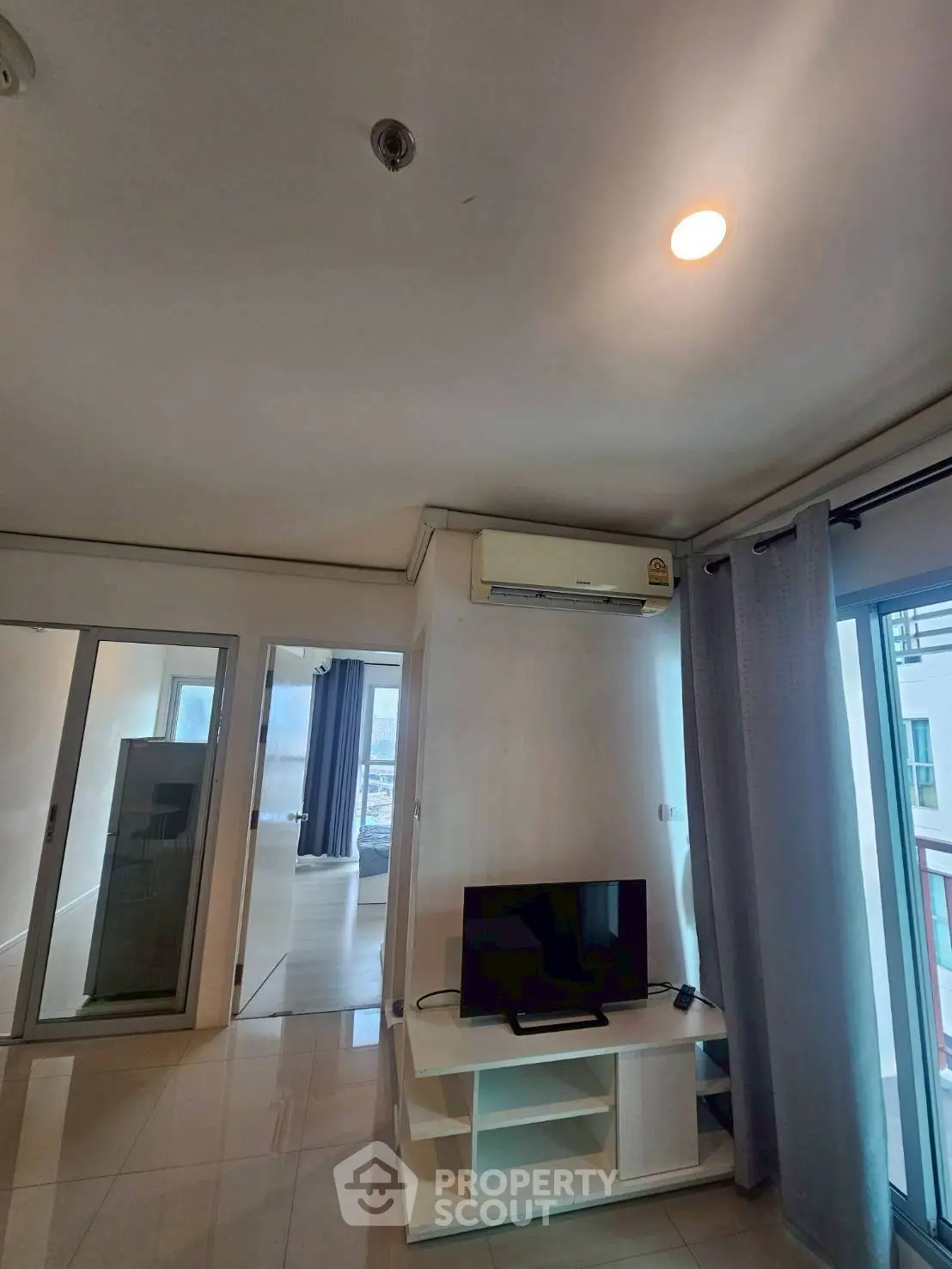 Modern apartment interior with TV, air conditioning, and large windows for natural light.