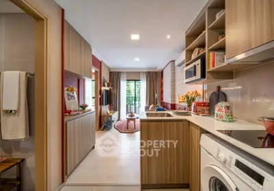 Modern open-layout kitchen with washing machine and stylish decor leading to a cozy living area with balcony view.