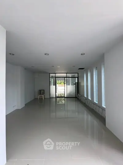 Spacious empty room with large windows and glossy tiled floor, ideal for customization.