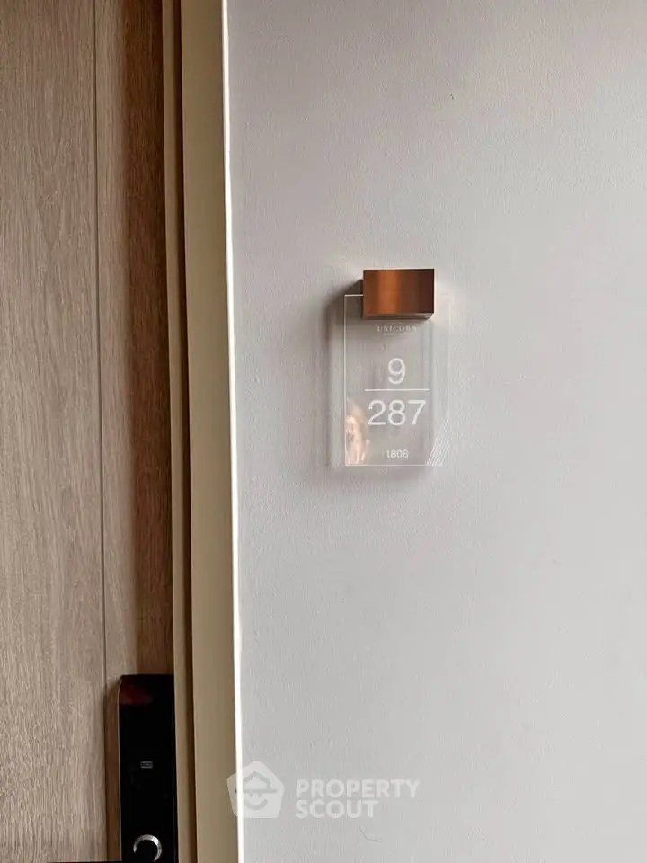 Modern apartment door with sleek electronic lock and stylish room number display.