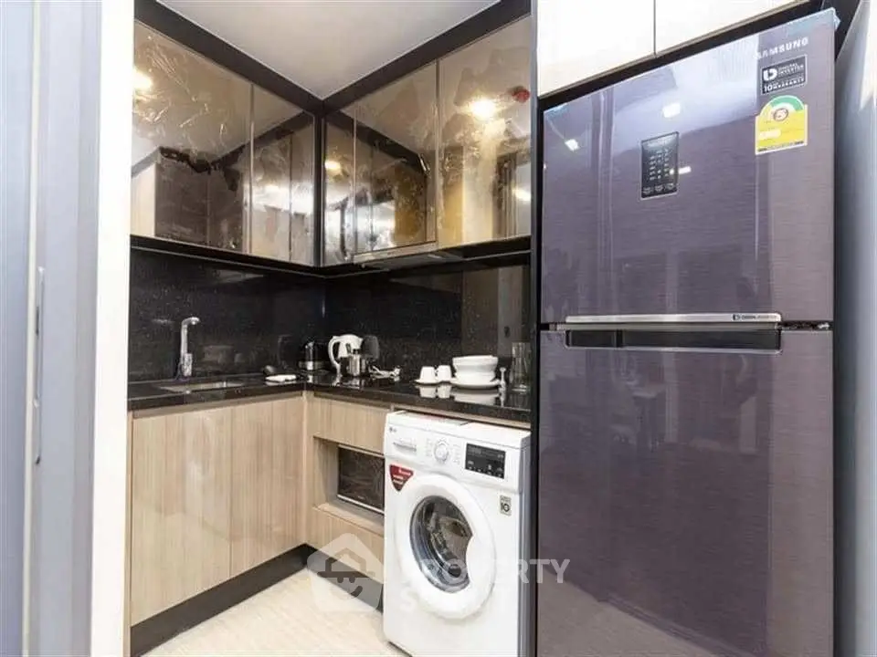 Modern kitchen with sleek appliances and washing machine in compact layout