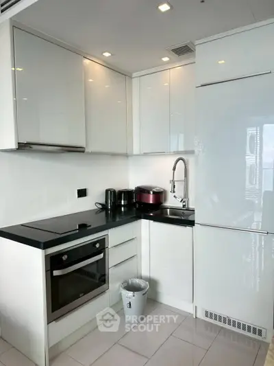 Modern compact kitchen with sleek white cabinets and built-in appliances.
