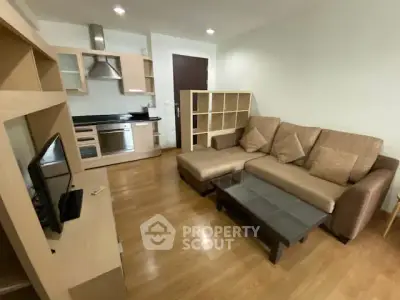 Modern living room with open kitchen, cozy sofa, and wooden flooring in a stylish apartment.