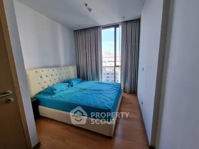 Modern bedroom with large window and city view, featuring a stylish bed and wooden flooring.