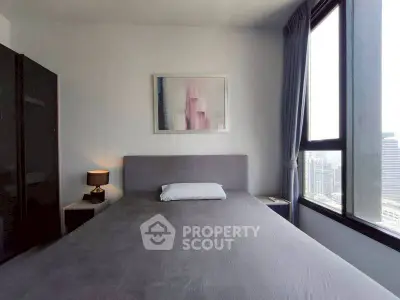 Modern bedroom with large windows and city view, featuring minimalist decor and stylish artwork.
