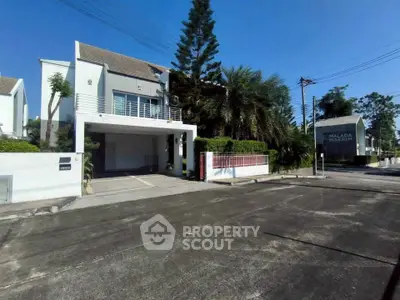 Modern two-story house with spacious driveway and lush greenery in a serene neighborhood.