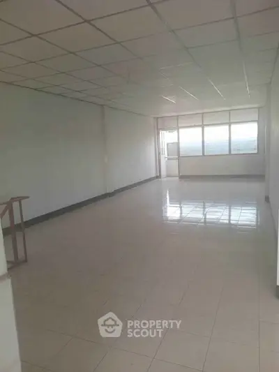 Spacious empty room with tiled floor and large windows, ideal for customization.
