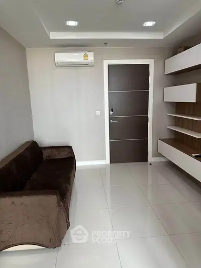 Modern living room with sleek brown sofa and wall-mounted shelves, featuring minimalist design and air conditioning.