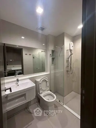 Modern bathroom with glass shower and sleek fixtures in contemporary apartment.